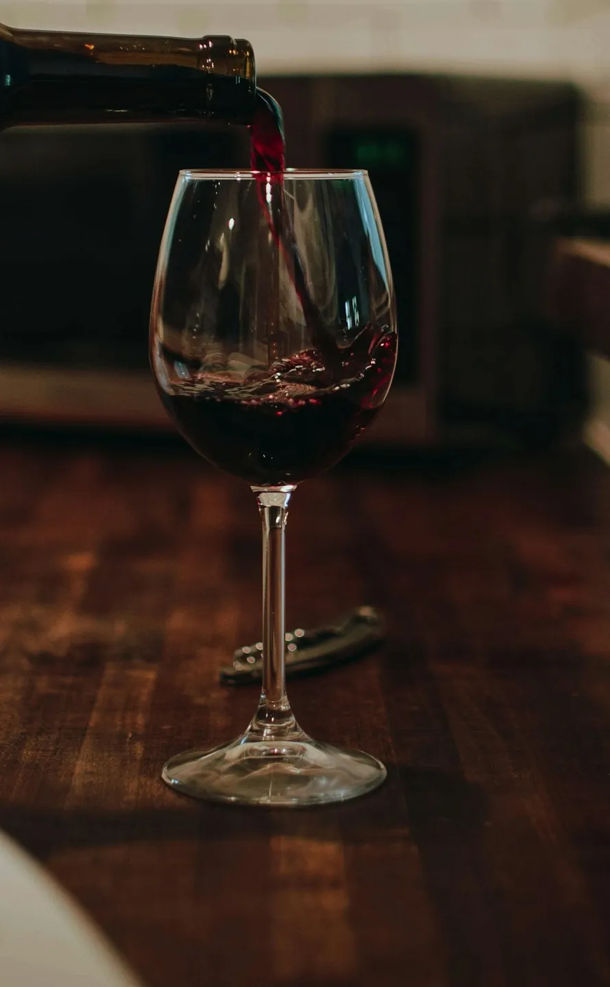 Un calice di Merlot versato sul tavolo di legno